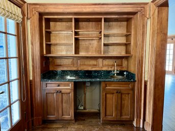 A Marble Top Wood Paneled Bar With Copper Sink