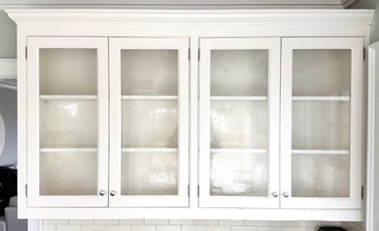 A Run Of Painted Wood And Bubbled Glass Paneled Upper Cabinets