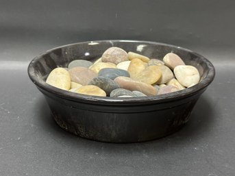 A Shallow Glazed Ceramic Bowl Full Of River Stones