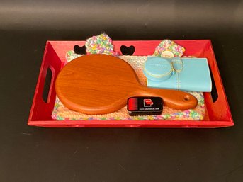 A Red Wood Tray With An Mix Of Items: Hand Mirror, Notebook & More