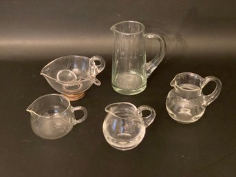 A Grouping Of Small Pitchers & Creamers In Clear Glass