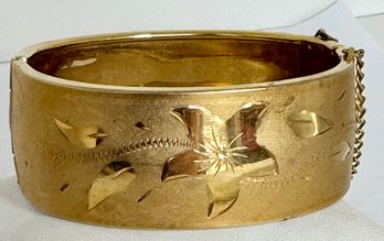 WIDE GOLD TONE BANGLE BRACELET WITH FLOWER DESIGN