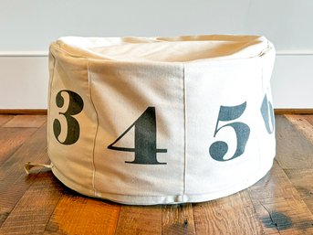 A Canvas Pouf With Industrial Numbers Stenciled By The Land Of Nod