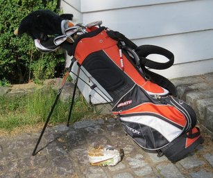 A Set Of Slazenger Wrath Golf Clubs With Bag, Balls, Tees, And Fiberglass Bag Stand