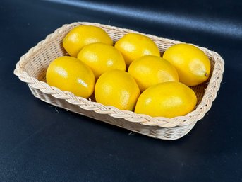 A Shallow Woven Basket Filled With Faux Lemons