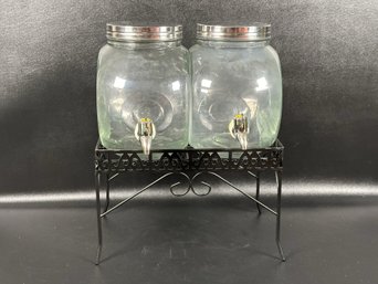 A Pair Of Glass Beverage Dispensers On A Metal Wire Stand