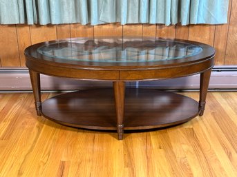 A Transitional Oval Coffee Table With A Beveled Glass Top & Lower Shelf