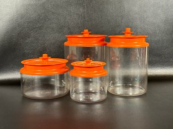 A Vintage Tupperware Canister Set In Clear Acrylic With Orange Push-Button Lids