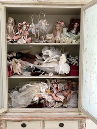 An Assortment Of Dolls And Decor - Cabinet Contents