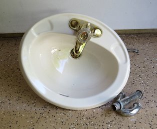 An Ivory Drop In Lavatory Sink With Moen Faucet In Brass Finish