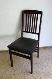 A Folding Wooden Chair With Padded Seat