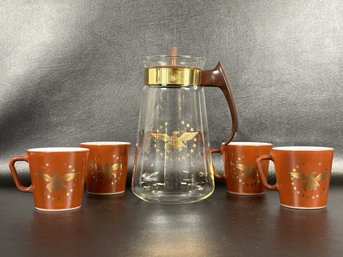 A Vintage Coffee Set By Pyrex With Carafe & Mugs Featuring A Gold Eagle Pattern