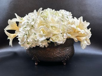 A Large Display Of Faux Blossoms In An Embossed Copper Pot