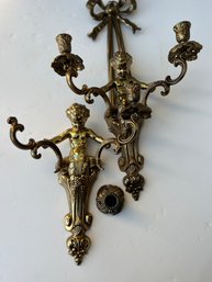 A Pair Of Decorative Brass Cherub Wall Sconces That Hold Two Candles Each