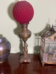 FIGURAL BRASS OIL LAMP WITH CRANBERRY GLASS SHADE AND HESSIAN SOLDIER