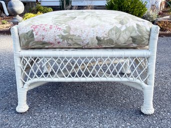 A Vintage Wicker Ottoman With Floral Cushion