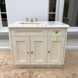 A Custom Vanity With Marble Top And Gold Toned Brass Faucet