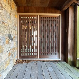 A Front Door  With Side Lite Panel And Distinctive Midcentury Wood Privacy Screens