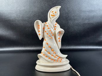 A Decorative Ceramic Ghost With Orange Studs, Set On A Lighted Base