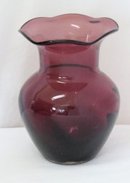 A Cranberry Colored Glass Vase With Rippled Edge