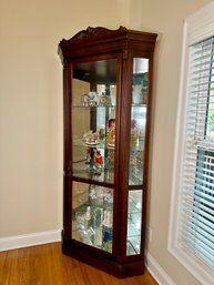A Stunning Corner Curio Cabinet With Mirror Back And Glass Shelves