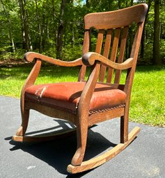An Antique Carved Wood Rocking Chair With Distressed Leather Seat