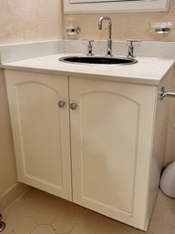 A White Vanity With A Corian Top And Stainless Steel Sink And Chrome Hardware