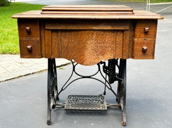 An Early 20th Century New Home Sewing Machine In Oak Case With Wrought Iron Base