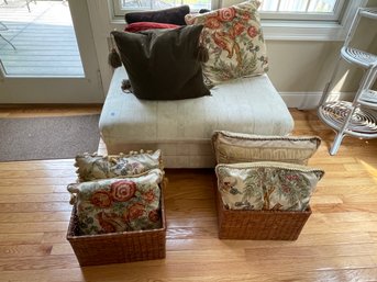 AN OTTOMAN, TWO RATTAN BASKETS, AND NINE DECORATIVE THROW PILLOWS