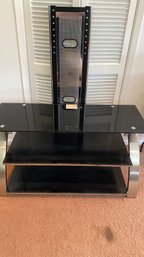A Black Glass TV Stand With Attached TV Mount