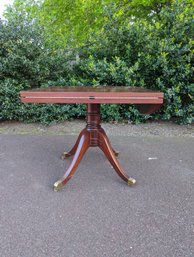 A Square Mahogany Stained  Drop Leaf Pedestal Table