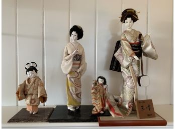 Four Asian Dolls On Wooden Platforms