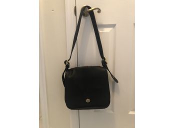 Black Leather Coach Bag With Brass Accents And A Long Adjustable Strap