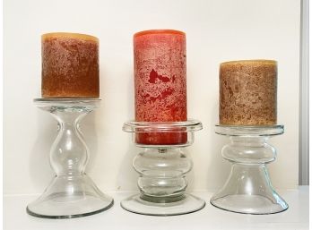 A Trio Of Blown Glass Candle Holders And Large Candles