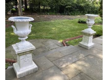 Pair Of Metal Urns On Concrete Stands With Bell Motif