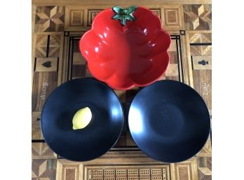 A Pair Of Black Oven To Table Serving Bowls And A Red Tomato Shaped Bowl