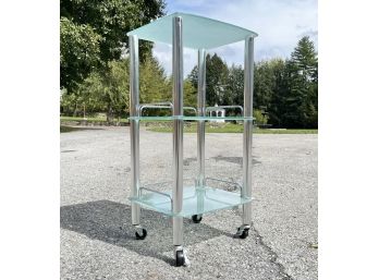 A Glass And Chrome Rolling Shelf Unit