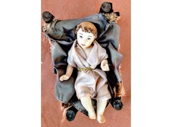 Adorable Miniature Ceramic Baby Jesus In Silk Clothing Lying In A Manger