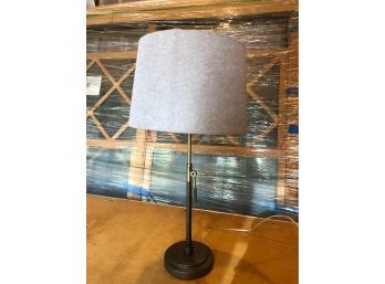 A Desk Lamp With Brass Base And Linen Shade