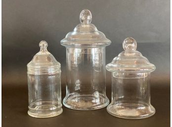 A Set Of Three Glass Apothecary Jars With Lids