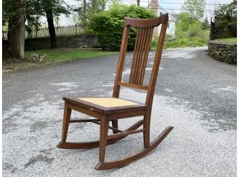 An Antique Oak Rocking Chair With Cane Seat