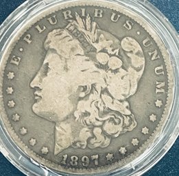 1897-O MORGAN SILVER DOLLAR COIN - IN PLASTIC CAPSULE