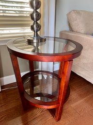 (A) ROUND CHERRY WOOD ACCENT TABLE WITH GLASS TOP & BOTTOM SHELF - 22'W BY 26'H