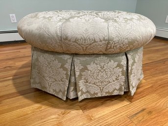 Round Tufted Ottoman With A Pleated Skirt And Caster Wheels, Upholstered In A Floral Damask Fabric.