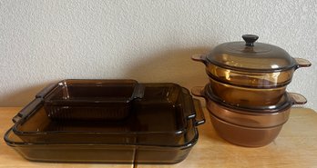 Three Amber Glass Baking Dishes In Various Sizes And Two Round Dutch Ovens