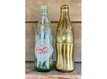 Two Decorative Vintage Reproduction Coke Bottles, One Clear One Gold Colored Metal