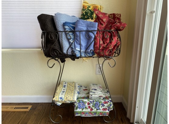 Metal Plant Stand Filled With Table Clothes And Napkins