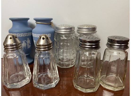 A Grouping Of Clear Glass Salt And Pepper Shakers With Lids And Grecian Inspired Small Vessels
