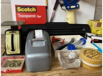 A Collection Of Home Office Supplies Including Tape Dispensers, Postage Scales And Tacks