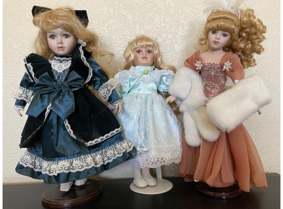 A Pair Of Three Porcelain Dolls On Stands With Ornate Formal Dresses
